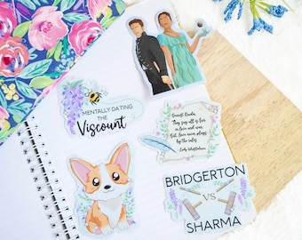 May include: A set of five stickers featuring a quote from the book Bridgerton, a cartoon corgi, a couple, and two Bridgerton vs Sharma stickers. The stickers are printed on clear vinyl and have a glossy finish.