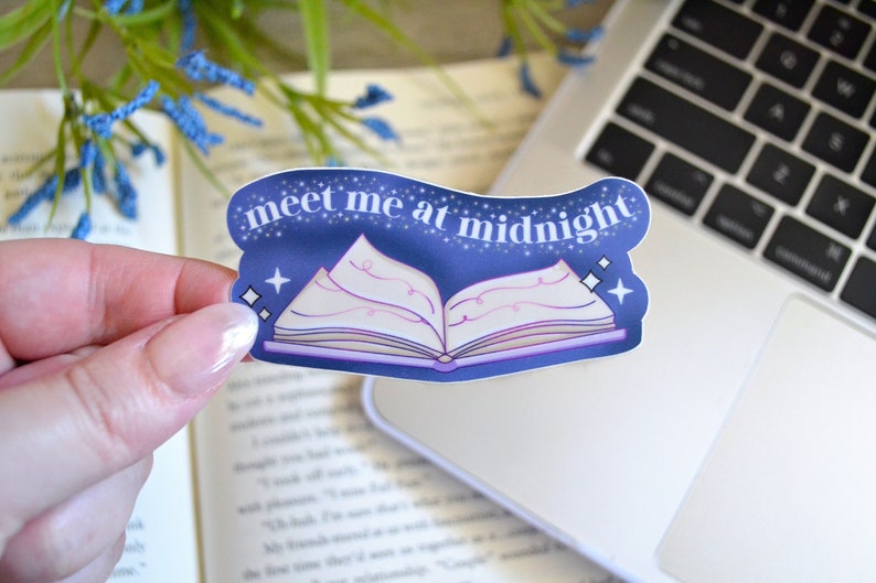 May include: A blue and purple sticker with a book and the text "meet me at midnight".