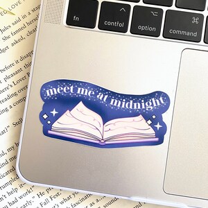 May include: A blue and white sticker with a book design and the text "meet me at midnight". The sticker is on a silver laptop.
