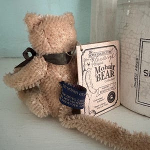 Pu&ograve; includere: Un orsacchiotto vintage in mohair marrone di The Boyd's Collection, con un nastro scuro e un'etichetta. L'etichetta recita "Original Mohair Bear Collection" e "Adams F. Bearington". L'orso &egrave; realizzato in nuovo materiale, poliestere e ha un'etichetta blu.