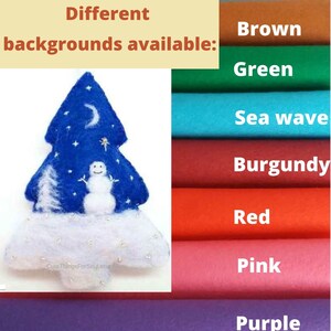 May include: A felt Christmas tree ornament featuring a blue background with a white snowman, a crescent moon, and stars. The base is white with small silver accents. The image includes text stating Different backgrounds available.