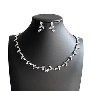 May include: A silver-toned necklace and matching earring set featuring a delicate vine motif. The jewellery is adorned with clear, marquise-cut stones arranged in a leaf-like pattern along the chain and the stud earrings, creating a cohesive set.