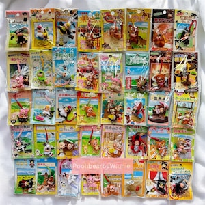 Puede incluir: Colección de pequeños llaveros japoneses empaquetados individualmente. Los llaveros presentan diseños de animales y personajes, con ilustraciones coloridas y texto japonés. La colección incluye una variedad de colores y estilos.