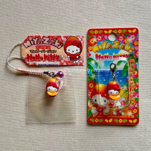 May include: Hello Kitty merchandise featuring a duck-themed design. The image includes a keychain, a charm, and a tag, all with the Miyazaki Hello Kitty theme. The items are in a clear plastic bag and on a colorful card.