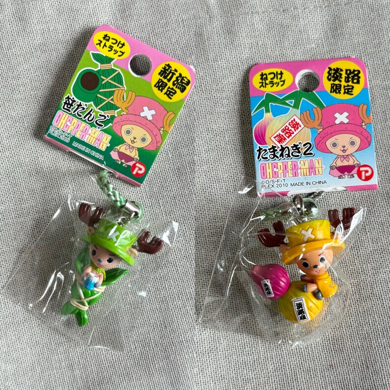 May include: Two One Piece Chopper Man keychains. One is green and the other is yellow. Each keychain has a pink and green tag with Japanese text and a Chopper Man character illustration. The tags read "Niigata Limited" and "Awaji Limited".
