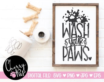 Könnte beinhalten: Ein weißes Schild mit braunem Rahmen, auf dem in Schwarz "Wash Your Paws" mit einer Pfotenabdruckgrafik und einem Herz steht. Das Schild befindet sich vor einem weißen Ziegelmauerhintergrund.