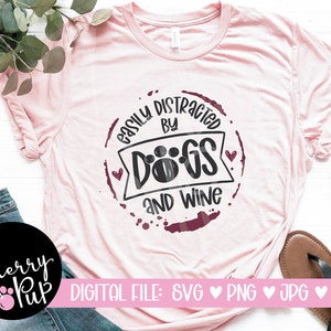 Pu&ograve; includere: Maglietta rosa con un grafico circolare marrone che dice "Easily Distracted by Dogs and Wine".
