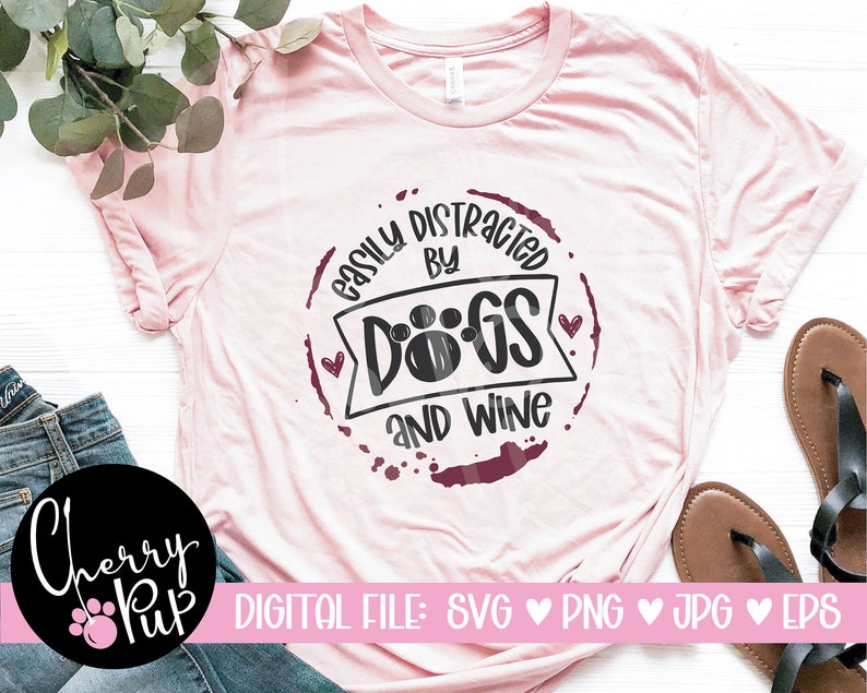 Pu&ograve; includere: Maglietta rosa con un grafico circolare marrone che dice "Easily Distracted by Dogs and Wine".
