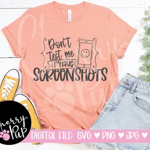 Könnte beinhalten: Ein pfirsichfarbenes T-Shirt mit dem Text "Don't test me I have screenshots" und einem Telefonsymbol mit einem Smiley. Der Text ist schwarz und das Telefonsymbol ist schwarzweiß.