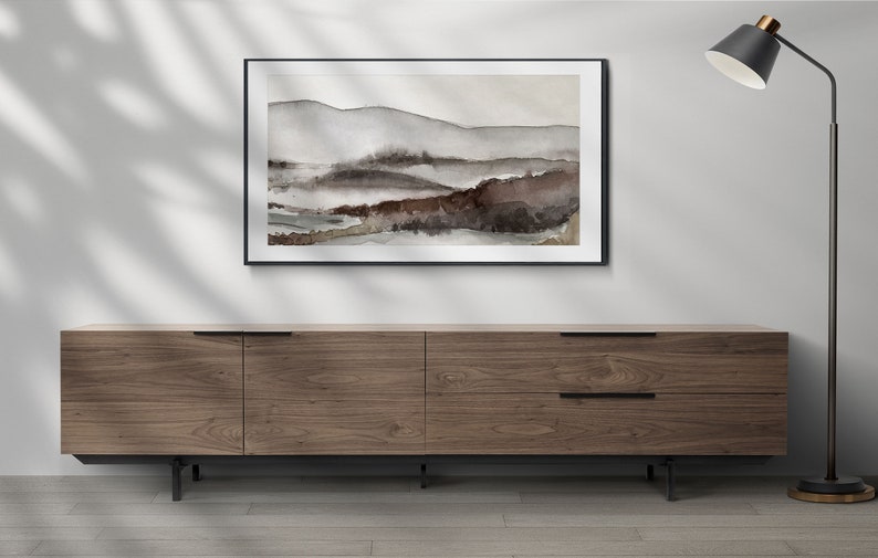 May include: A framed watercolor painting of a landscape with brown and gray hills and a black floor lamp with a black shade.