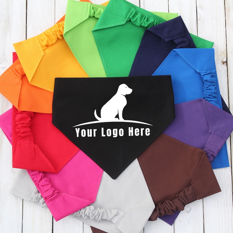 Assorted custom dog bandanas with scrunchie necks arranged in a circle on a white wood background. Each bandana is a solid color, including red, orange, yellow, green, blue, purple, pink, brown, gray, and black. The center black bandana features a white dog silhouette and the text “Your Logo Here,” showcasing the option for custom branding. Scrunchie Dog Bandana, Custom Logo Pet Bandana, Customized Dog Bandana, Gift for Dog Mom, New Dog Gift, Dog Groomer Gift, Bulk Order Bandana