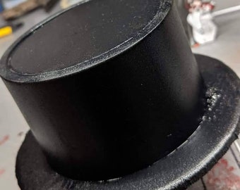May include: A black top hat with a wide brim. The hat is made of a smooth, matte material.
