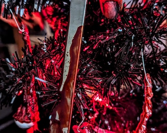 May include: A black Christmas tree decorated with red and white ornaments, including a bloody knife and a bloody hand.