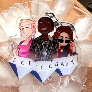 May include: Three cartoon characters, a woman with blonde hair, a man with brown skin and a man with brown hair, are depicted on a clear acrylic charm. The charm is surrounded by ice cubes in a glass bowl. The charm reads "ICE ICE BABY".