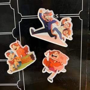 May include: Three cartoon character stickers featuring characters from the animated series Gravity Falls. The first sticker shows the characters Dipper and Mabel Pines, the second sticker shows the character Stan Pines, and the third sticker shows the character Wendy Corduroy.
