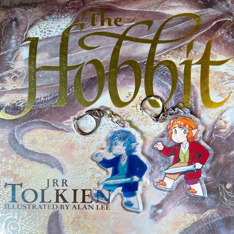 K&ouml;nnte beinhalten: Zwei Schl&uuml;sselanh&auml;nger mit Figuren aus "Der Hobbit" von J.R.R. Tolkien. Die Figuren sind ein blau gekleideter Elf mit einem Schwert und ein rot gekleideter Hobbit mit einem Schwert.