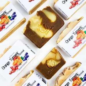 May include: Four bars of handmade soap with a swirl of orange and brown. The soap is labelled "Orange Turmeric with Patchouli" and "BEE Zero Waste".