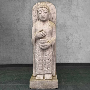 Może przedstawiać: Biała kamienna statua stojącego Buddy trzymającego miskę w dłoniach. Statua jest rzeźbiona z misternymi detalami i ma spokojny wyraz twarzy.