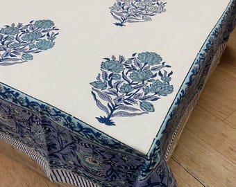 May include: White tablecloth with a repeating floral pattern in shades of blue. The border features a complementary floral design. The tablecloth is made of a soft fabric and is suitable for a dining table.