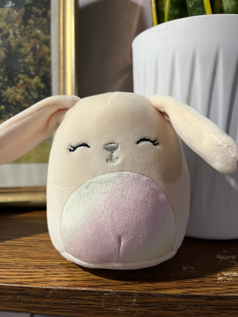 Puede incluir: Un juguete de peluche de conejo con un cuerpo marr&oacute;n claro, una cara blanca y una barriga de color arco&iacute;ris. El conejo tiene ojos y nariz bordados.