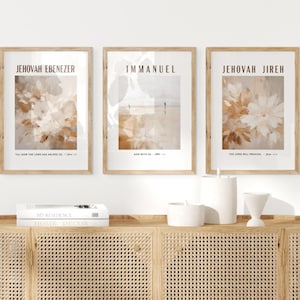 May include: Three rectangular wall art prints in light wood frames. The left print features abstract beige and white flowers with the text JEHOVAH EBENEZER. The center print shows a beach scene with the text IMMANUEL. The right print shows flowers with the text JEHOVAH JIREH.