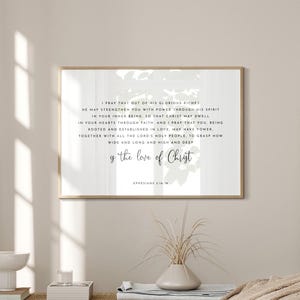 Può includere: Una stampa incorniciata con una cornice color oro, con una scritta con le parole "y the love of Christ". La stampa è esposta in una stanza dai toni neutri con una panca, oggetti decorativi e un letto con una coperta beige.