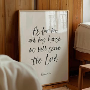 Könnte beinhalten: Ein gerahmter Druck mit dem Text "As for me and my house we will serve the Lord" in schwarzer Schrift. Der Druck befindet sich in einem hellen Holzrahmen und wird in einem Schlafzimmer gezeigt.
