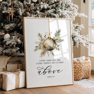 Könnte beinhalten: Ein gerahmter vertikaler Druck mit einer goldenen Weihnachtskugel, die an einem Tannenzweig hängt, mit dem Text: Every good gift and every perfect gift is from above, James 1:17. Das Design ist auf einem weißen Hintergrund mit schwarzer Schrift zentriert.