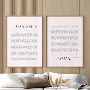 May include: Two vertical framed wall art prints featuring black text on a light background. The left print displays the title Romans 12 followed by biblical scripture. The right print contains additional scripture text ending with the word amen.
