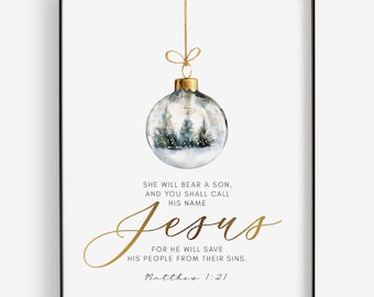 May include: A white background with a gold Christmas ornament with a winter scene inside. The ornament is hanging from a string with a bow. The text "SHE WILL BEAR A SON, AND YOU SHALL CALL HIS NAME Jesus FOR HE WILL SAVE HIS PEOPLE FROM THEIR SINS. Matthew 1:21" is written in gold below the ornament.
