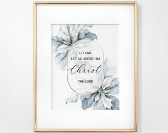 May include: A framed wall art print featuring watercolor poinsettia flowers in shades of blue and white. Centered within a gold oval frame is the text O COME LET US ADORE HIM Christ THE LORD in a mix of serif and script typography.