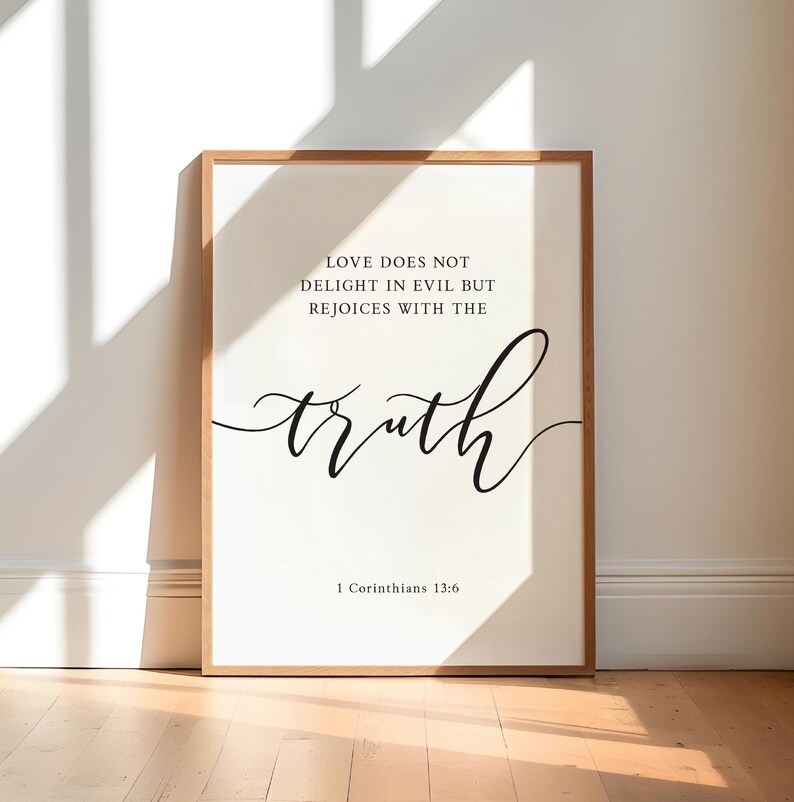 May include: A framed print featuring the words "LOVE DOES NOT DELIGHT IN EVIL BUT REJOICES WITH THE truth" and "1 Corinthians 13:6" in black script. The frame is light brown, and the background is white.