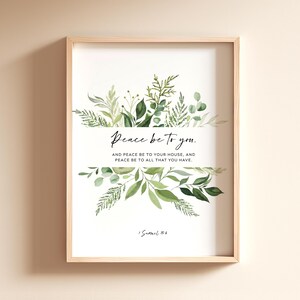 May include: A framed print with a light wood frame. The artwork features the text "Peace be to you" with botanical illustrations of green leaves and foliage. The quote continues with "AND PEACE BE TO YOUR HOUSE, AND PEACE BE TO ALL THAT YOU HAVE."