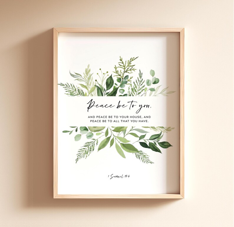 May include: A framed print with a light wood frame. The artwork features the text "Peace be to you" with botanical illustrations of green leaves and foliage. The quote continues with "AND PEACE BE TO YOUR HOUSE, AND PEACE BE TO ALL THAT YOU HAVE."