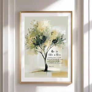 Könnte beinhalten: Ein gerahmter Kunstdruck mit einer abstrakten Malerei eines Baumes mit grünen und gelben Blättern. Das Kunstwerk enthält den Text "He is like a tree" und einen Bibelvers. Der Rahmen ist goldfarben.