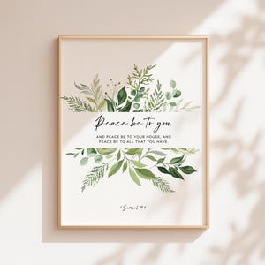 May include: A framed art print with a gold border. The print features the text "Peace be to you" above and below a banner of green leaves and foliage. The text "AND PEACE BE TO YOUR HOUSE, AND PEACE BE TO ALL THAT YOU HAVE" is below the main text. The scripture reference "1 Samuel 15:6" is at the bottom.