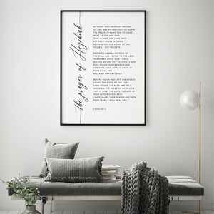 May include: A framed print with the text "the prayer of Hezekiah" in elegant script. The black frame surrounds a white background with a Bible verse. The print is displayed in a modern living room setting.