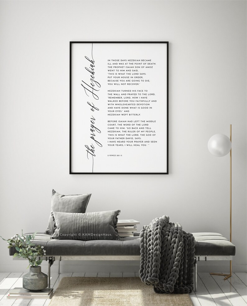 May include: A framed print with the text "the prayer of Hezekiah" in elegant script. The black frame surrounds a white background with a Bible verse. The print is displayed in a modern living room setting.