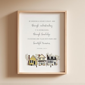 May include: A framed print with a watercolor illustration of three houses and a quote from Proverbs 24:3-4. The quote reads: "By wisdom a house is built, and through understanding it is established, through knowledge its rooms are filled with rare and beautiful treasures."