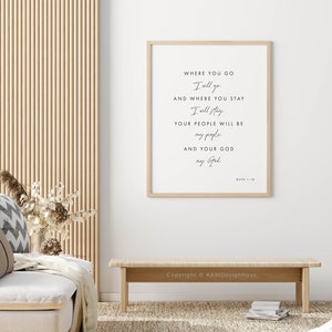 May include: A framed print with a white background and black text. The text reads "Where you go I will go and where you stay I will stay. Your people will be my people and your God my God. Ruth 1:16". The print is hanging on a white wall.