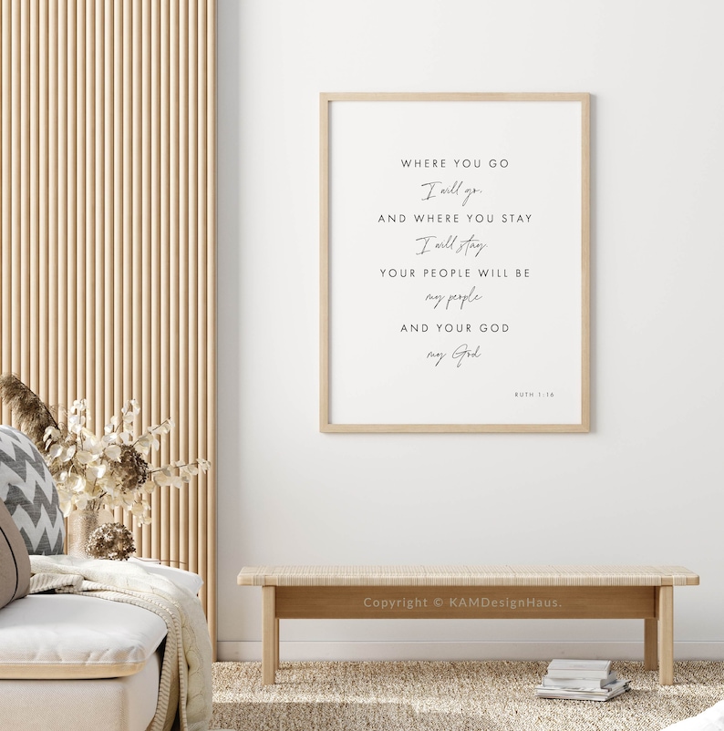 May include: A framed print with a white background and black text. The text reads "Where you go I will go and where you stay I will stay. Your people will be my people and your God my God. Ruth 1:16". The print is hanging on a white wall.
