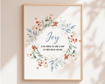 May include: A framed print featuring a watercolor wreath with red berries and blue leaves. The word "Joy" is written in cursive, with the text "TO THE WORLD, THE LORD IS COME! LET EARTH RECEIVE HER KING" below. The frame is gold.