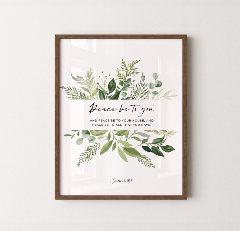 May include: Framed art print with a white background, featuring the text "Peace be to you." and a botanical design of green leaves and foliage. The frame is a warm brown color. The text also includes "And peace be to your house, and peace be to all that you have."
