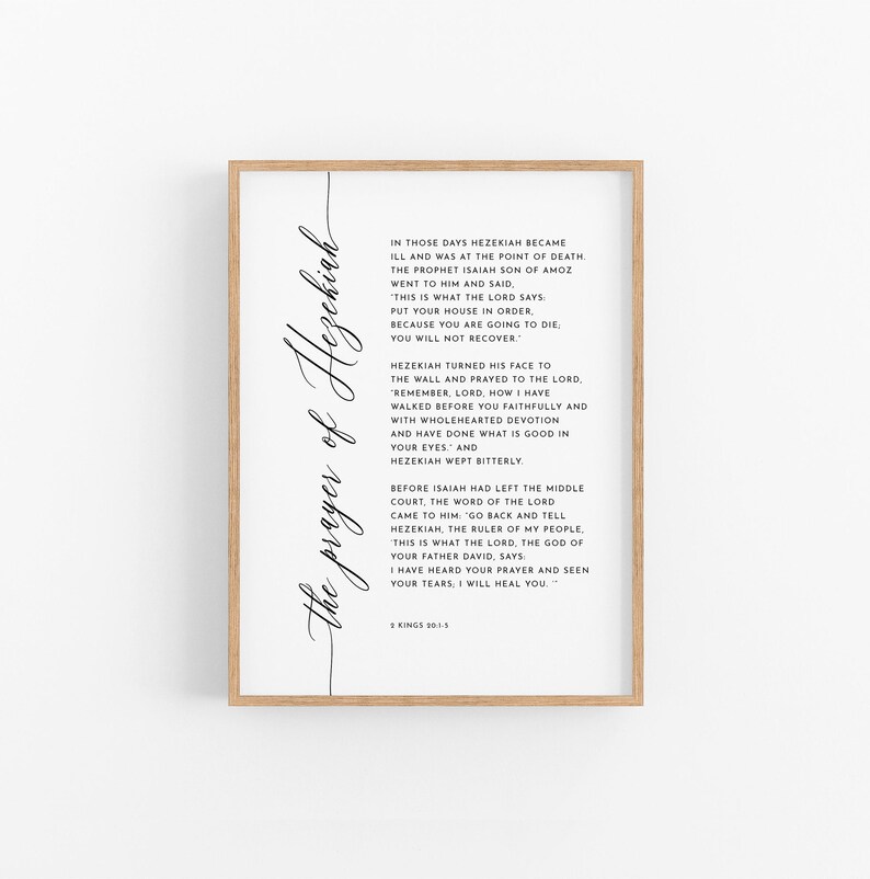 May include: A framed print with the text "The prayer of Hezekiah" in elegant script. The print features a passage from 2 Kings 20:1-3, printed in black on a white background, within a light brown wooden frame.