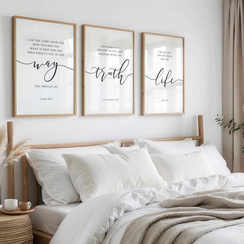 May include: Three framed prints with inspirational quotes in black script on a white background. The frames are light brown. The prints are above a bed with white bedding and a beige throw. The text includes "way", "truth", and "life".