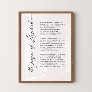 May include: A framed print with the text "the prayer of Hezekiah" in elegant script. The print features a passage from 2 Kings 20:1-5, set against a white background, encased in a wooden frame.