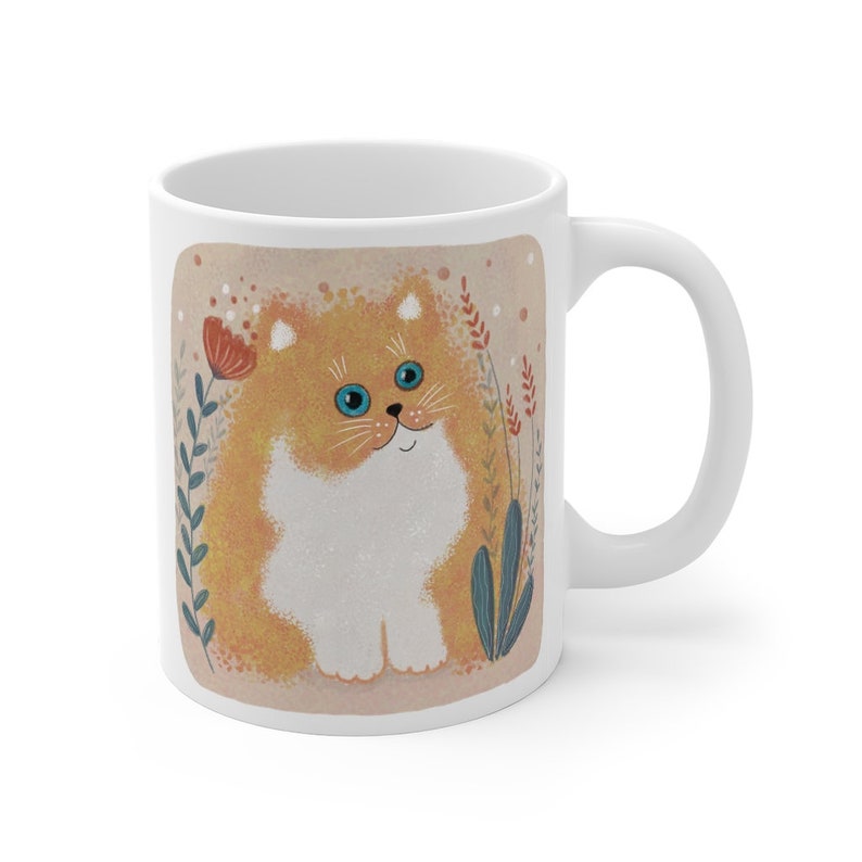May include: White ceramic mug with a cartoon illustration of a fluffy orange cat with blue eyes sitting in a field of flowers. The cat is looking directly at the viewer.