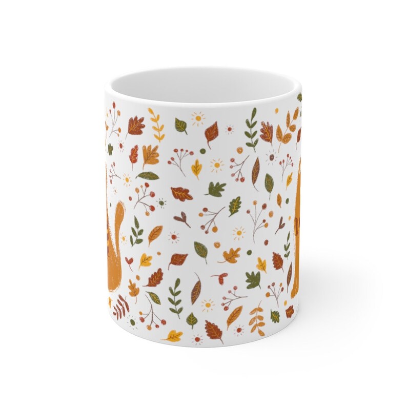 May include: White ceramic mug with a pattern of orange, yellow, and green leaves, berries, and flowers. The pattern is repeated all over the mug.