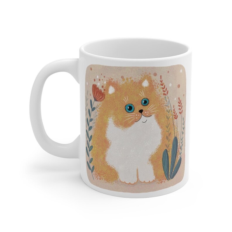 May include: White ceramic mug with a cartoon illustration of a fluffy orange cat with blue eyes sitting in a field of flowers. The cat is smiling and has a white chest.