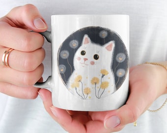 May include: White ceramic mug with a white cat with pink nose and yellow eyes surrounded by yellow dandelions on a black background.